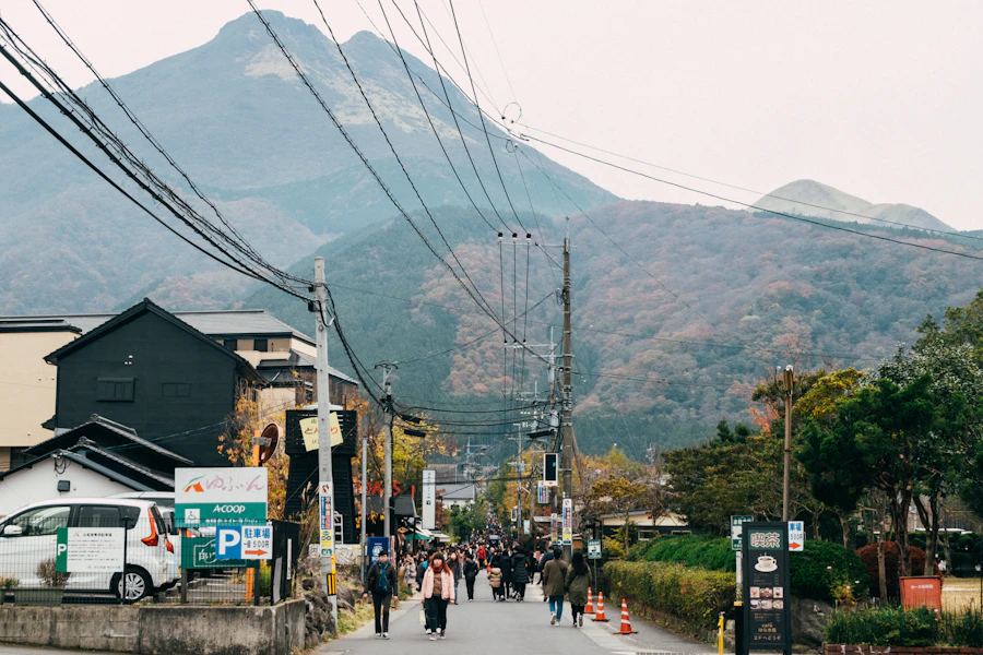 Travellers walking along a street beneath the mountains in Yufuin