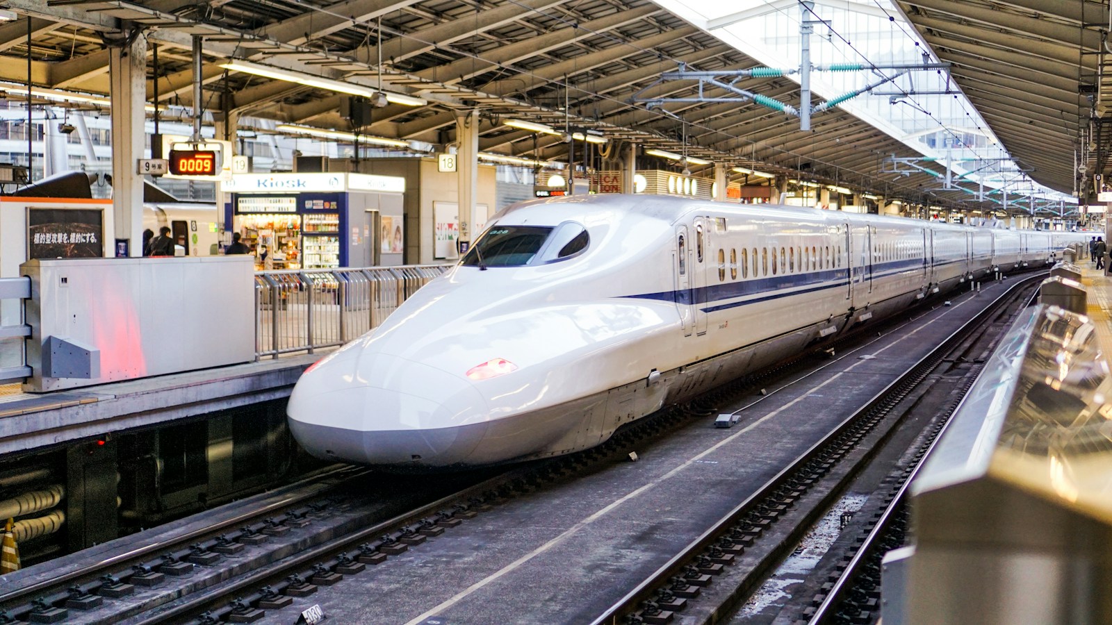 A Shinkansen train at a Japanese station platform, photographed by Fikri Rasyid; general onward-travel context.